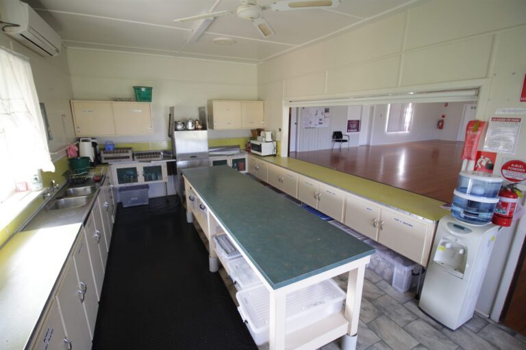 The Hub's kitchen, with a long preparation bench and the servery opening through to the hall
