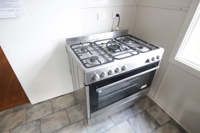 A large stainless steel gas range with six burners and an oven, in the Hub's kitchen