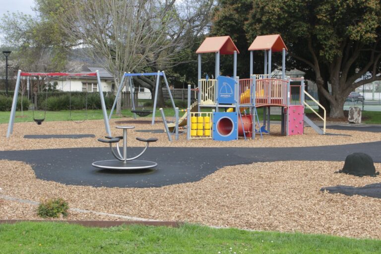 The playground beside the Hub, with a climbing frame, swings and a slide on soft fall