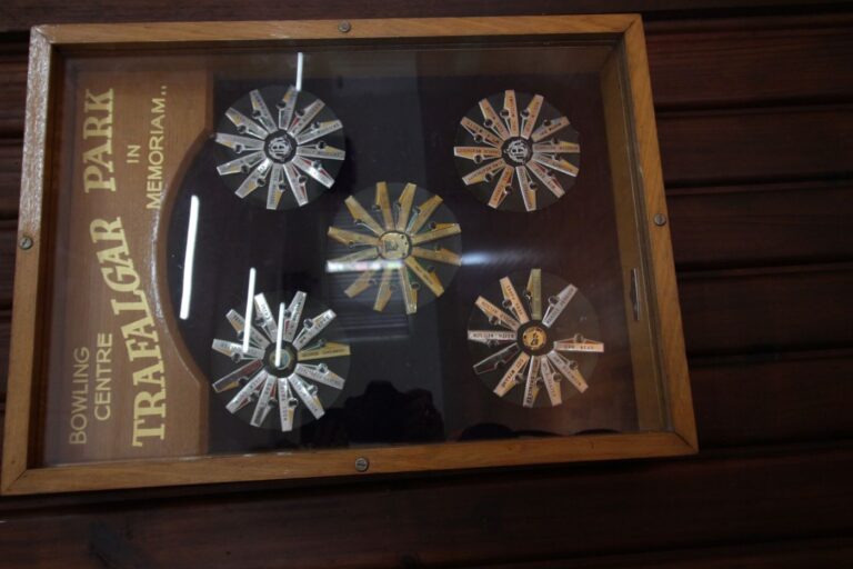A glass memorial cabinet holding engraved bowls trophies, mounted on the hall wall